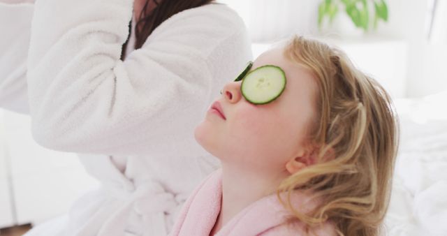 Caucasian mother and daughter having fun in bedroom. putting cucumber slices on their eyes. enjoying quality time at home during coronavirus covid 19 pandemic lockdown