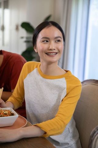 Young woman enjoying meal with friends at home dining table