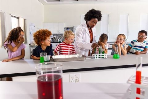African american teacher leading hands-on chemistry experiment with elementary students