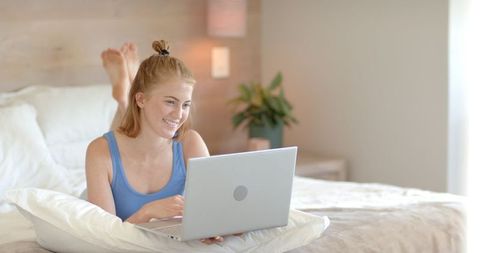 Woman Relaxing on Bed Using Laptop in Modern Cozy Bedroom