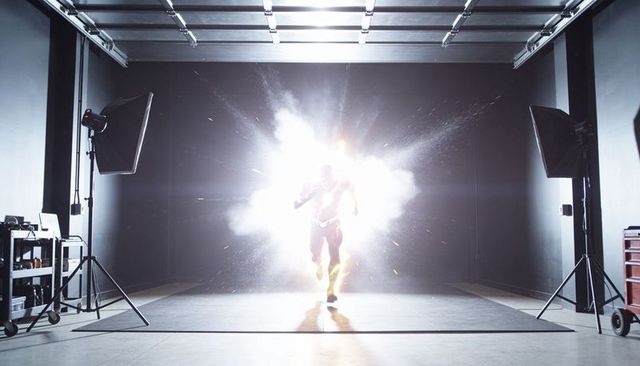 Superhero sprint through explosion on soundstage with dramatic backlight and sparks