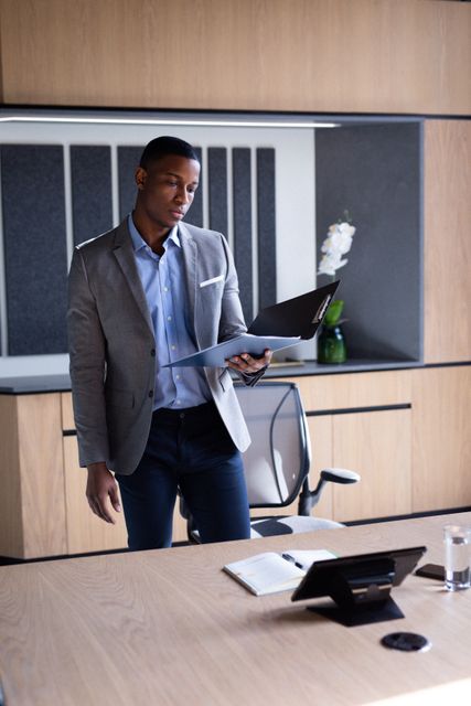 Thoughtful african american businessman reading file standing in office. business, working at a modern office.