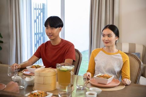 Young couple enjoying noodle salad at casual home dining