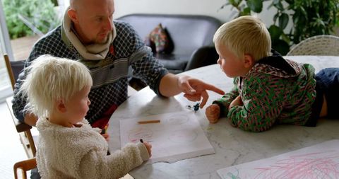 Father Assisting Children with Drawing at Home