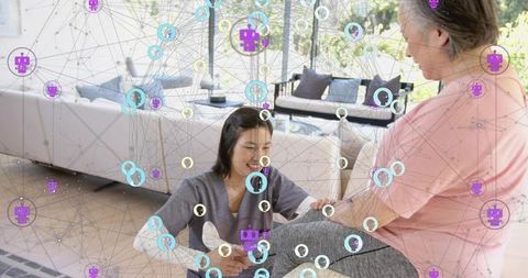 Homecare caregiver assisting senior on sofa with telemedicine digital network overlay