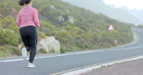 Woman Jogging on Scenic Mountain Road for Fitness
