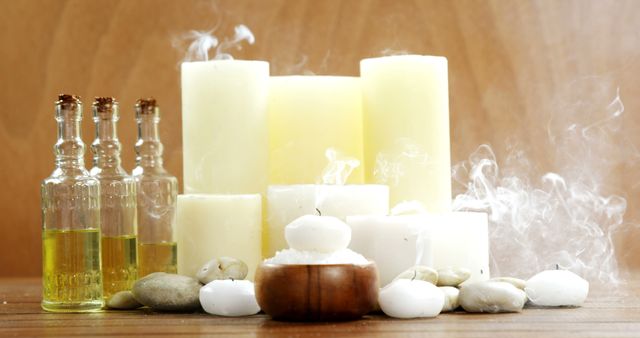 Candles, rocks, olive oil bottles and white smoke on brown wooden background. Welness and spa, relaxation, body care and wellbeing.