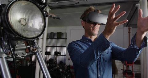 Mechanic Wearing VR Headset Manipulating Virtual Motorcycle Parts in Garage Workshop