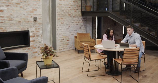 Diverse male and female colleagues in discussion using tablet and laptop in office. Casual office, business, communication, teamwork and work, unaltered.