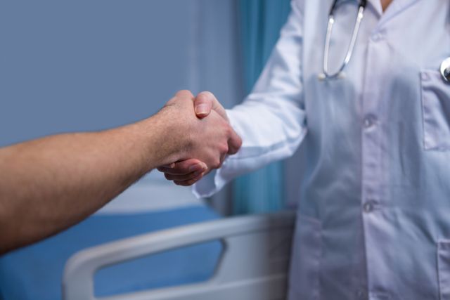 Mid section of nurse and doctor shaking hands at hospital