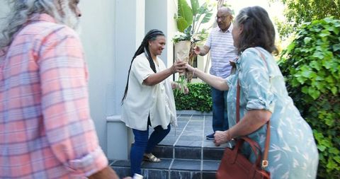 Diverse senior friends arriving with flowers for gathering