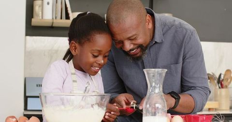 Joyful African American Father and Daughter Baking Together in Kitchen