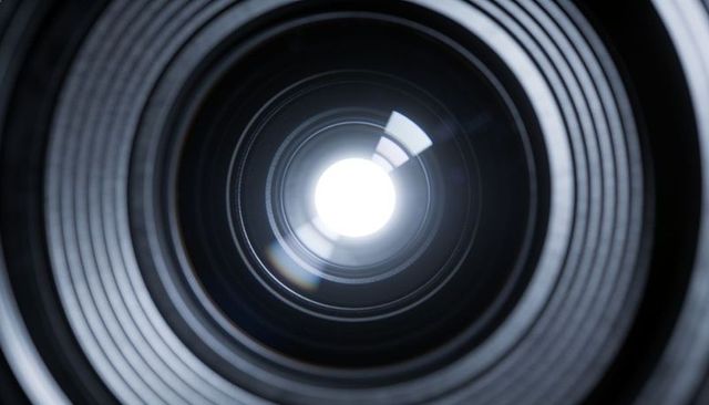 Macro close-up revealing camera lens aperture blades, concentric rings and reflective optics
