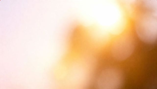 Golden hour sunburst bokeh with warm lens flare, radiant halo glow abstract background