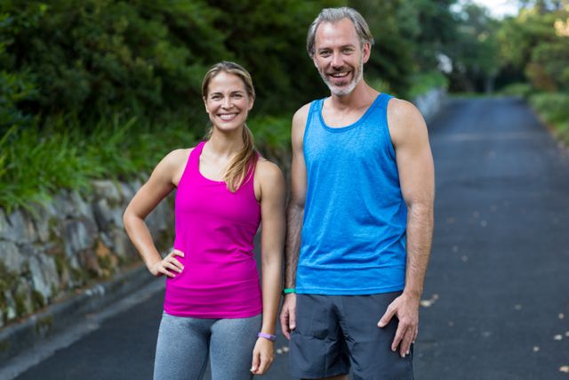 Smiling athletic couple standing on road after jogging