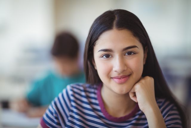 Portrait of happy schoolgirl sitting in classroom at school