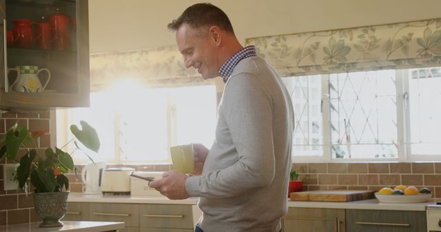 Smiling Man Interacting with Smartphone in Sunny Kitchen - Download Free Stock Images Pikwizard.com