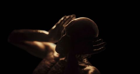 Distressed figure in darkness holding head in pain