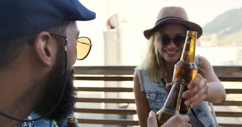 Friends toasting beers on rooftop during party