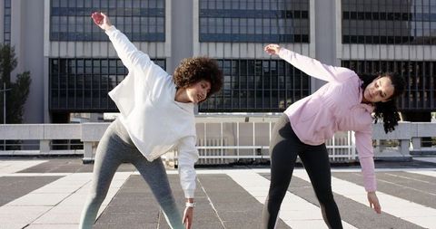 Diverse women stretching on urban rooftop during sunny morning workout in athleisure