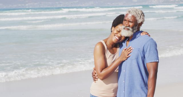 Happy african american couple embracing and looking away on sunny beach. healthy and active time beach holiday.