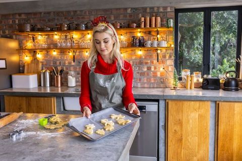 Blonde Woman Baking Holiday Cookies in Rustic Farmhouse Kitchen Holding Tray of Dough