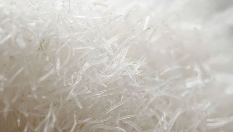 Macro of translucent needle crystal cluster with fibrous glassy texture and soft bokeh