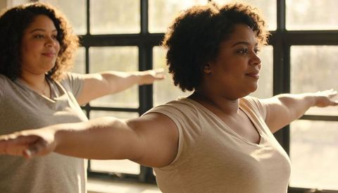 Women stretching arms in sunlit studio practicing gentle wellness exercise for beginners