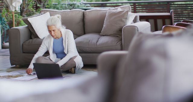 Senior biracial woman sitting on floor using laptop - Download Free Stock Photos Pikwizard.com