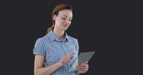 Mid Adult Woman Using Tablet Smiling in Casual Business Outfit on Dark Background