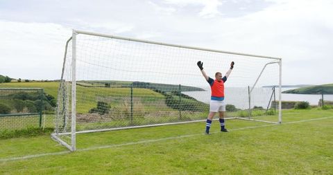 Goalkeeper in soccer goal celebrating victory at idyllic coastal field