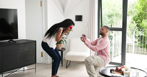 Surprise engagement proposal at home with rose and ring