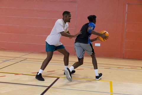 African american men playing basketball indoors dribbling, pivoting and defending