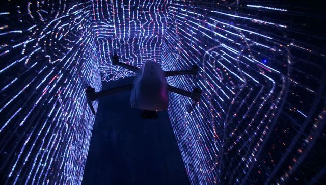 Hovering quadcopter inside neon led tunnel reflecting futuristic light trails