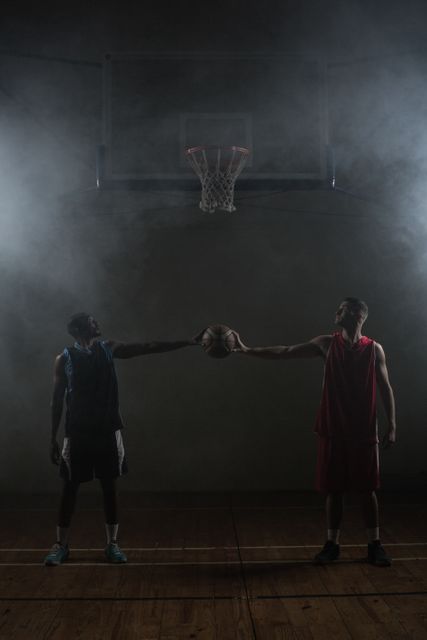 Two basketball player holding a single basketball in a gymnasium