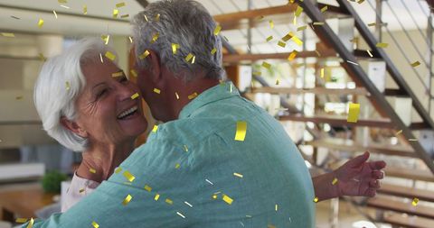 Joyful Senior Couple Dancing Amidst Confetti Celebration at Home