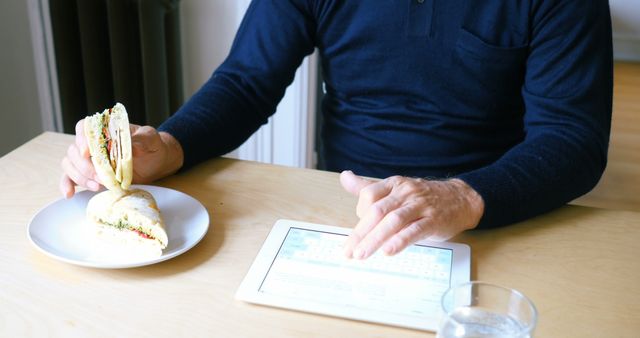 Man Eating Sandwich While Using Tablet at Breakfast Table - Download Free Stock Images Pikwizard.com