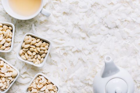 Healthy snacking with cashews and tea on coconut flakes background