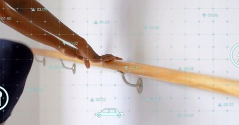 Mid-adult woman gripping wooden barre for ballet fitness rehab with augmented data overlay