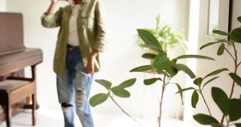 African american woman standing in bright minimalist living room near piano and plants