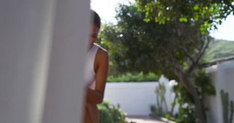 Elegant woman peeking around garden pillar