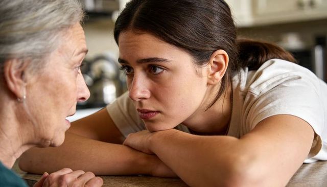 Young woman listening intently to elderly relative in emotional multigenerational moment