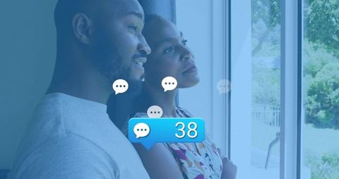 Young couple standing by sliding door looking toward garden with message bubble 38
