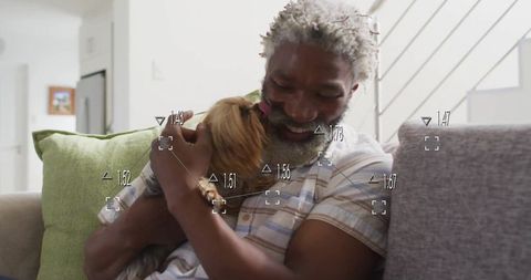 Happy Senior Man Embracing Cute Terrier Dog on Couch