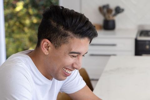Young african american man laughing at marble kitchen counter minimalist bright lifestyle