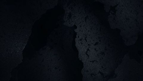 Dark peeling metal texture revealing granular specks and weathered patina close-up