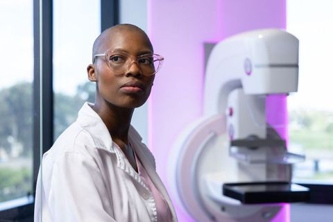 African american woman operating mammography machine in radiology clinic wearing white coat