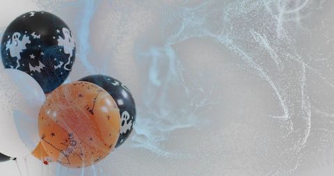 Halloween balloons drifting with ghost graphics and misty gray copy space for seasonal designs