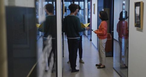 Team Collaboration in Modern Office Hallway with Glass Walls