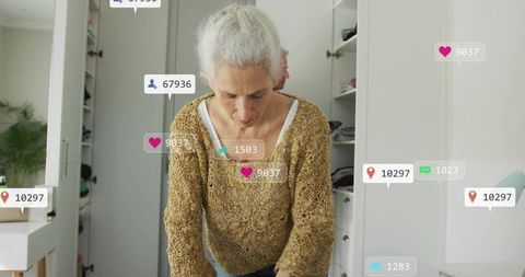 Mature woman organizing wardrobe with social media notifications in modern minimalist home